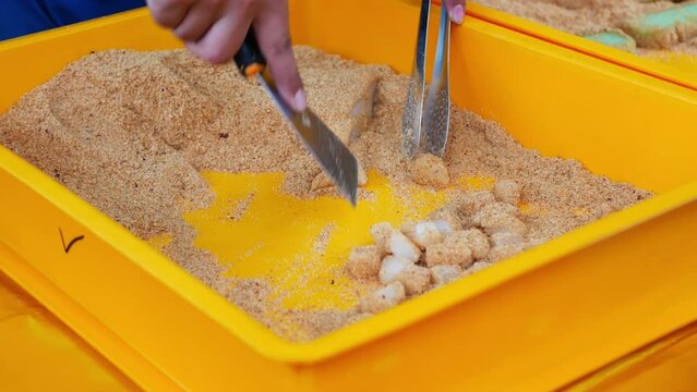 Close-up view of a hawker making muah chee street food, it is a steamed sticky dough basically made of glutinous flour, cut in small pieces and coated with sugar and fine or crushed roasted peanuts