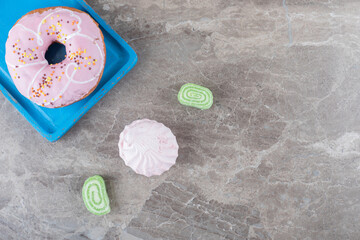 Marmelades and a cookie next to a donut on a platter on marble background