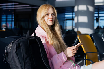 A young woman while waiting for a plane at the airport. A traveler with a mobile phone.