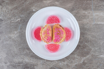 Marmelades and small buns with nut filling on a platter on marble background
