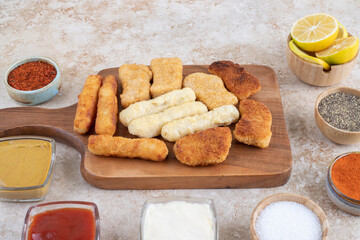 Chicken nuggets, cheese sticks and fried sausages witn variety of sauces and spices