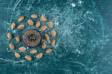 Circle of almonds around a small cake on blue background