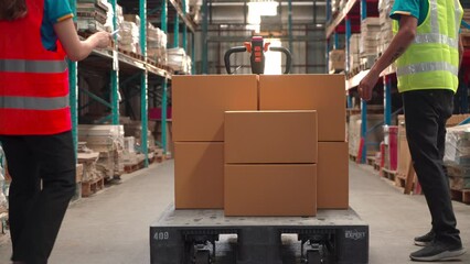 4K, Asian man worker lift cardboard box from wooden plate preparing to stock checking, staff carry products in warehouse store sending to logistic company, shipping  count the boxes for customers
