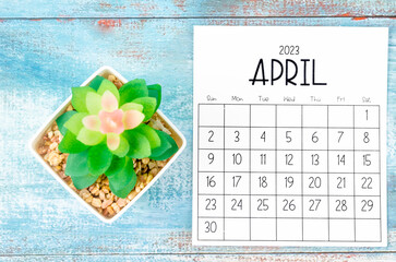 The April 2023 Monthly calendar with plant pot on wooden background.