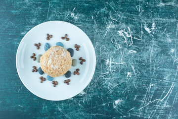 A platter with squirrel cake, candy rocks and coffee beans on blue background