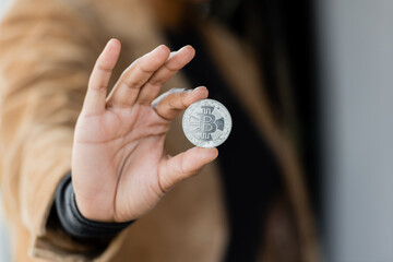 KYIV, UKRAINE - APRIL 27, 2022: Cropped view of african american businesswoman holding silver bitcoin.