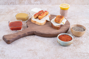 Grilled sausages and chicken nuggets on a sandwich toast served with sauces