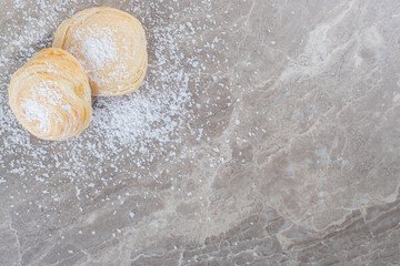 Vanilla powder and two flaky cookies on marble background