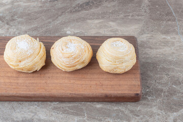 Three flaky cookies on a board on marble background