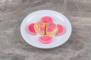 Marmelades and small buns with nut filling on a platter on marble background