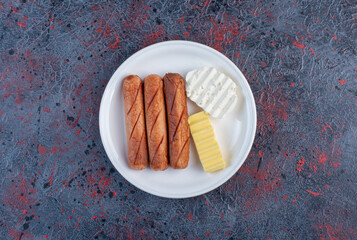 Grilled sausages with cheese slices in a plate