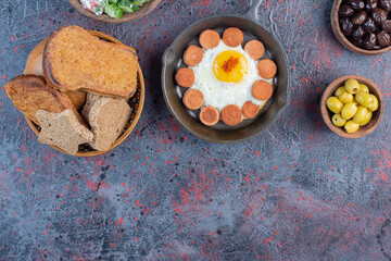 Fried egg served with grilled sausage and spices on a wooden platter