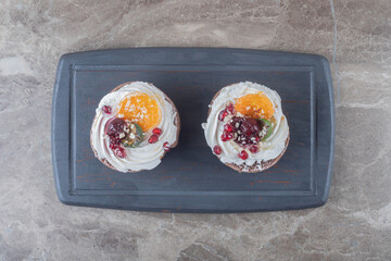 Two cakes on a navy board on marble background