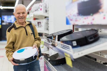 senor man pensioner buying Robotic vacuum cleaner in showroom of electrical appliance store
