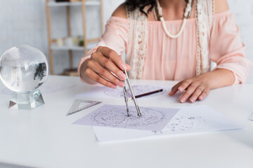 cropped view of blurred astrologist drawing celestial map at home.