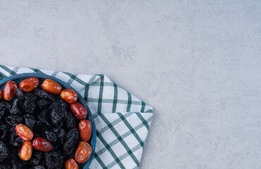 Dry black plums and dates in a blue platter