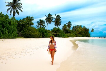 Fototapeta na wymiar Young woman walking on beach 