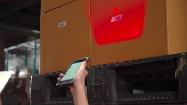 4K, hand using technology laser machine to check stock quality control in storehouse factory, close-up hand point inspect storage stack box parcels on a shelf in a large warehouse

