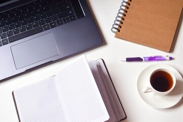 Office table top view stock photo. Laptop, open paper notebook, purple pen and cup of coffee. Workplace flat lay image, business background