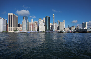 Fototapeta na wymiar View from a boat to East River with Manhattan and Brooklyn bridges landmark and other iconic buildings from New York City during a beautiful sunny day.