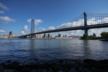View from a boat to East River with Manhattan and Brooklyn bridges landmark and other iconic buildings from New York City during a beautiful sunny day.