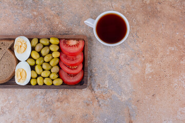 Breakfast board with bread slices, vegetable and a cup of tea