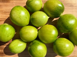 Green unripe tomatoes on a wooden board. Rustic style. Top view. Raw green tomato on table for dinner.