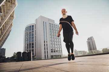 Fototapeta na wymiar Photo of focused jumper bearded retired grandpa jump skipping rope wear t-shirt shorts sneakers urban town outdoors