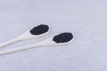 Fototapeta na wymiar Black cumin seeds in a wooden spoon on concrete background