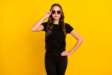 Photo of serious confident young woman wear black outfit arm dark eyeglasses isolated yellow color background