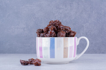 Dried sour cherry plums inside a dish isolated on concrete background