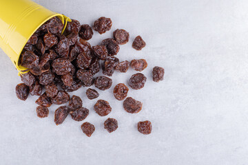 Brown dried cherries inside a dish on concrete background