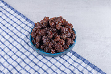 Brown dried cherries inside a dish on concrete background