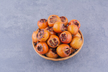 Medlars on a wooden platter on grey background
