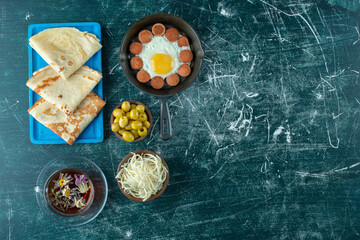 Breakfast menu on a wooden board with eggs, crepes and side foods
