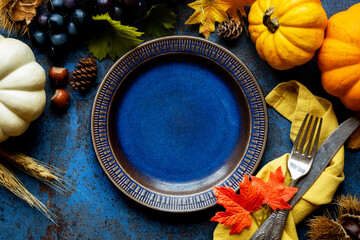 Hello Autumn banner with seasonal fall decorations - grapes, pumpkin, red leaves, chestnut and grain ears with a plate and vintage silverware. Thanksgiving celebration dinner concept with copyspace