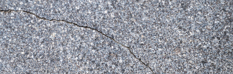 Old grey granite tiles are laid on the streets of the city. Banner of cracked granite tiles