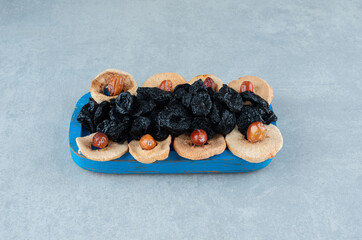 Dry black plums, jujube berries and apple slices on a blue platter