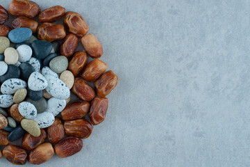 Brown dry dates in composition with colorful beach stones