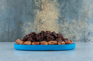 Dry black cherries and jujube berries in a blue platter