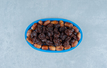 Fototapeta na wymiar Dried black plums with jujube berries in a blue platter