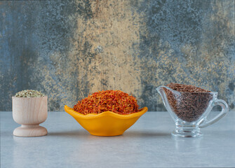 Cumin, anise and saffron in cups on blue background