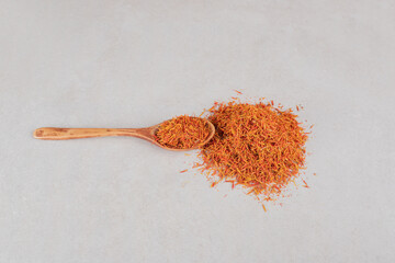 Red saffron seeds in a wooden spoon