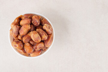 Yellow dry dates in a ceramic cup on concrete background