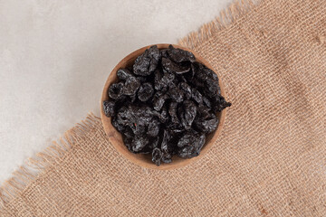 Dry black plums in a rustic wooden cup