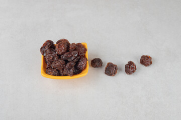 Dried brown plums in a ceramic cup