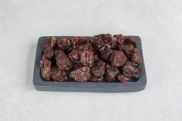 Dried brown plums on a wooden platter
