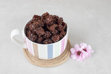 Dried brown plums in a ceramic cup
