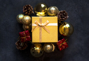 Christmas,new year flat lay with gift box framed with balls,small gift boxes and cones against darl blue background.Holiday card