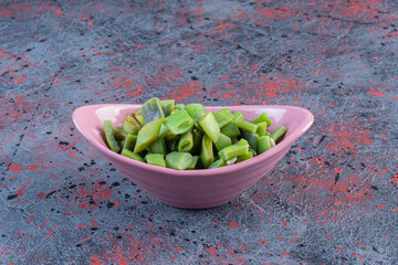 Oval bowl of chopped bean pulses on dark colored background